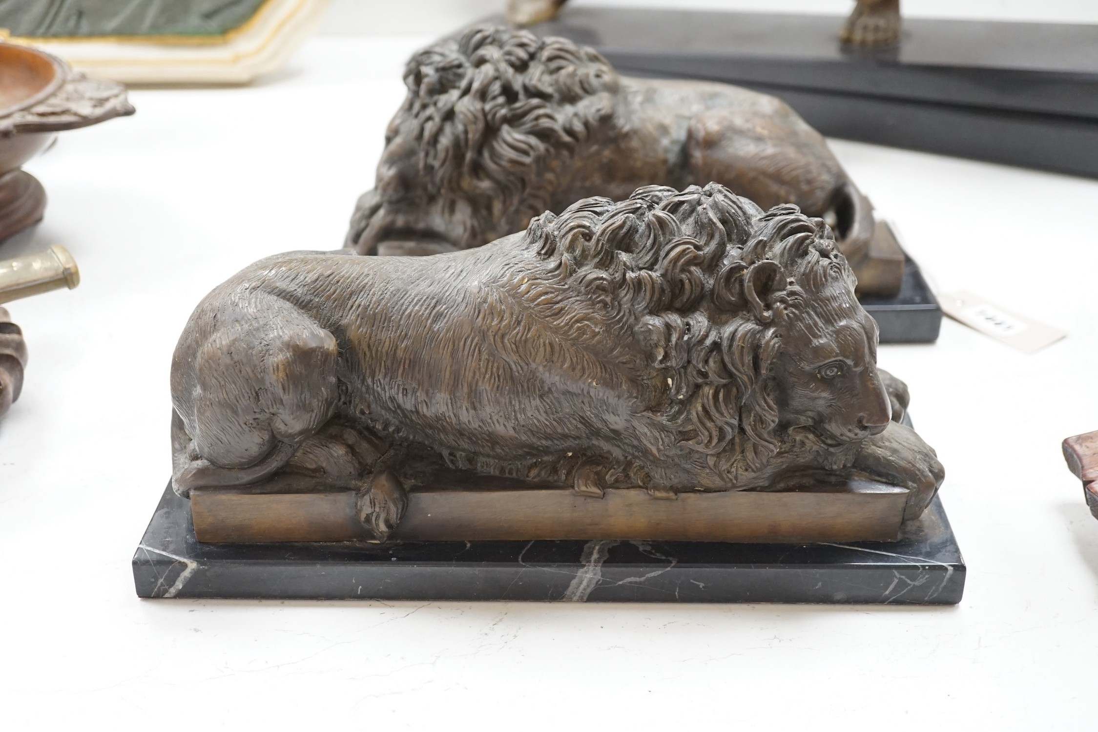 A pair of bronze recumbent lions on black marble bases 33cm